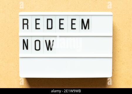 Lightbox with word redeem now on wood background Stock Photo