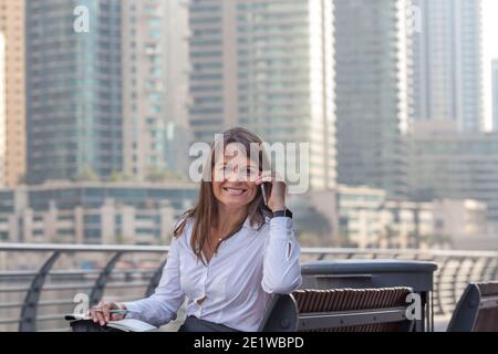 Great looking middle aged European business woman talking on the phone in Dubai Marina Stock Photo