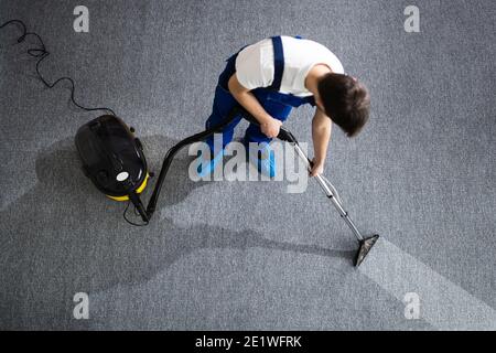 Janitor Cleaning Carpet With Vacuum Cleaner At Home Stock Photo