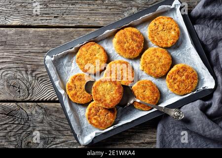 White fish cakes of white fish fillet: cod or haddock with potato and parsley, breaded in breadcrumbs and then baked in the oven, served on a sheet pa Stock Photo