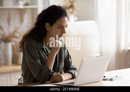 Young woman sit at desk working on laptop online Stock Photo