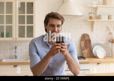 Smiling man relax at home using modern smartphone Stock Photo
