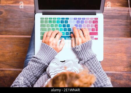 Top view of female caucasian hands working on coloured keyboard of laptop computer - concept of connected people and smart worrking with home technolo Stock Photo