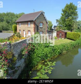 English cottage with colourful cottage garden, wall and river. Stock Photo