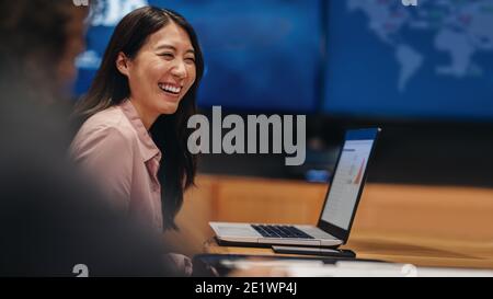 Smiling young woman sitting at table with laptop in meeting room. businesswoman in meeting with team in office. Stock Photo