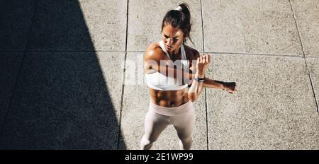 Top view wide angle shot of a sportswoman stretching arms. Woman doing warmup exercises. Stock Photo