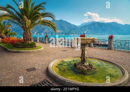 Cute water fountain and flowerd bed with palm trees on the promenade. Great location on the shore of the lake Como, Menaggio, Lombardy, Italy, Europe Stock Photo