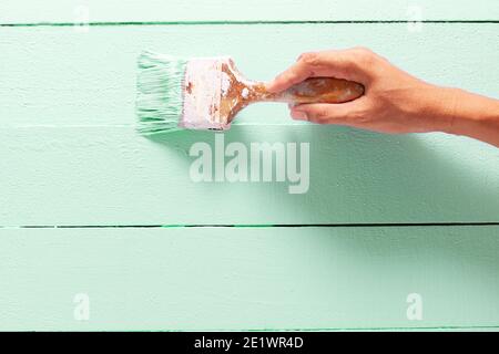 Close Up painter man Hand painting green color on wooden plank table with copy space,bright creative design interior and How to Paint Wooden Surface. Stock Photo