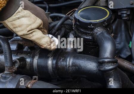 Car repair, car service concept. Gloved hand with wrench tightens  bolts in the engine compartment of  truck.  Selective Focus. Stock Photo