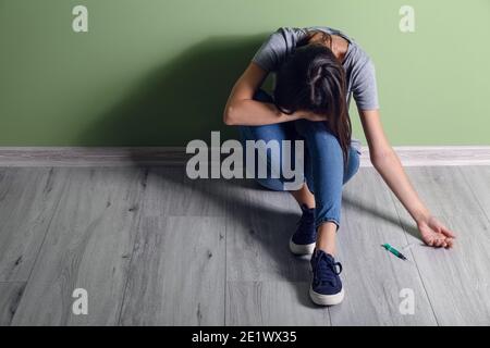 Female junkie sitting near color wall Stock Photo - Alamy