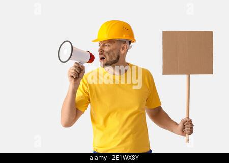 Protesting miner man with megaphone and placard on light background Stock Photo