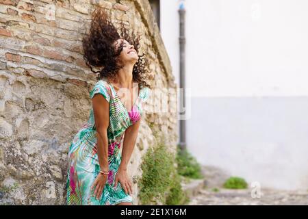 Beautiful brunette middle-aged woman wearing spring colorful dress outdoors Stock Photo
