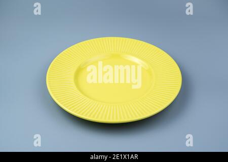 An empty yellow plate on a gray background. Stock Photo
