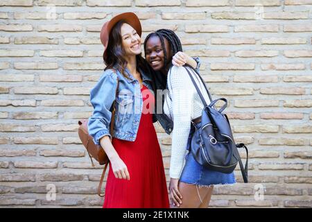Two friends hugging in urban background. . Multiethnic friends. Stock Photo