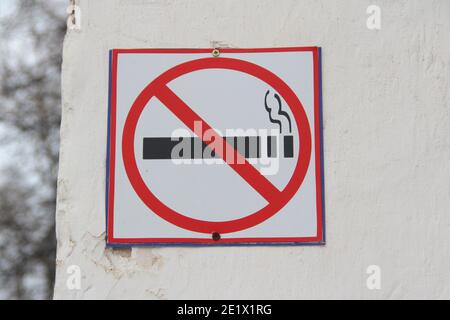 No smoking sign on white wall, concept of health care, smoking cessation. Smoking cigarette in a crossed out red circle. Stock photo with empty space Stock Photo