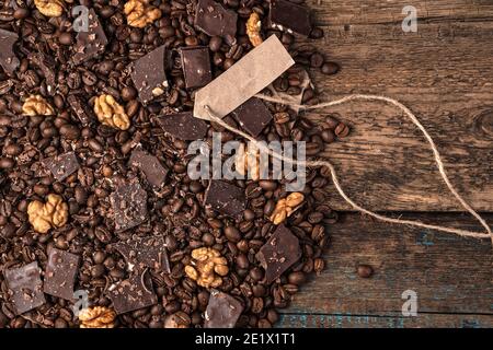 Pieces of chocolate, nuts and coffee on a wooden background. Stock Photo