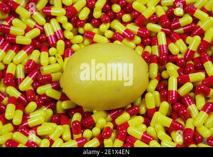Close up of one ripe raw lemon on medical colorful yellow red capsules - Vitamin c supplement concept (focus on center) Stock Photo