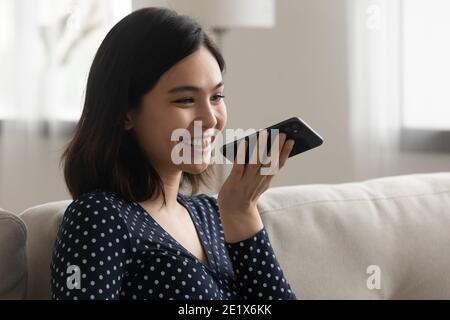Happy young korean asian woman sending voicemail. Stock Photo