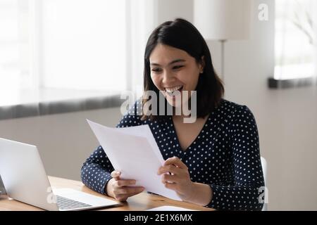 Euphoric smiling young mixed race worker getting job promotion letter. Stock Photo