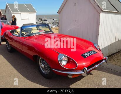 Classic Red E Type Jaguar  Open Top Sports car parked on seafront promenade near beach huts. Stock Photo