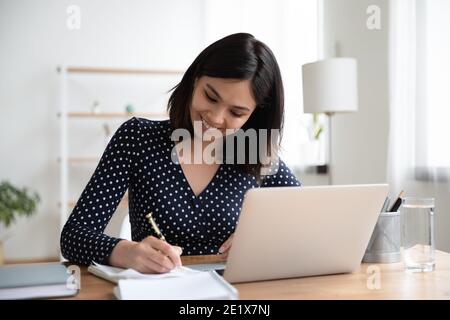 Happy young smart korean vietnamese woman enjoying studying online. Stock Photo