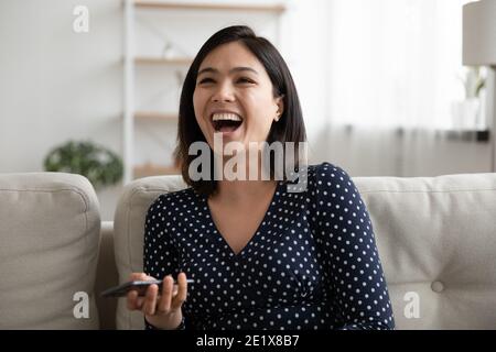 Emotional happy millennial asian woman laughing at funny mobile video. Stock Photo