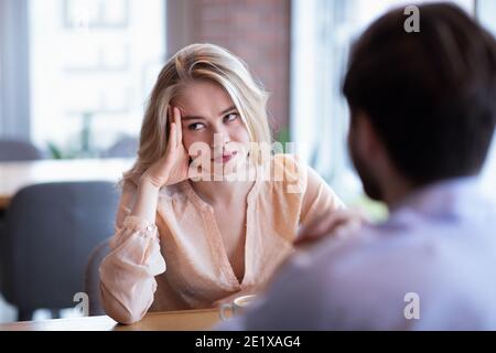 Young Caucasian woman disinterested in blind date, feeling bored with conversation at city cafe Stock Photo