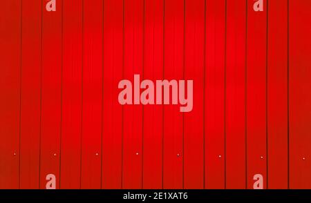red color corrugated zinc fence, closeup glossy metal plate for surrounding wall of construction site, garage door or roofing, abstract industrial tex Stock Photo