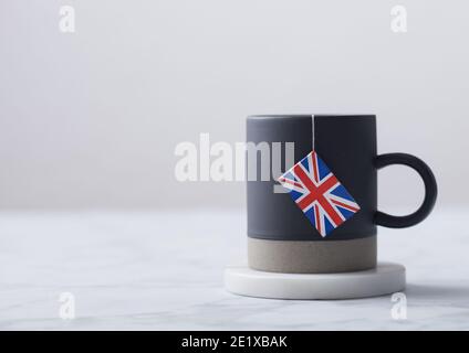 Teabag with flag of United Kingdom in grey ceramic cup on white background. Afternoon tea tradition Stock Photo
