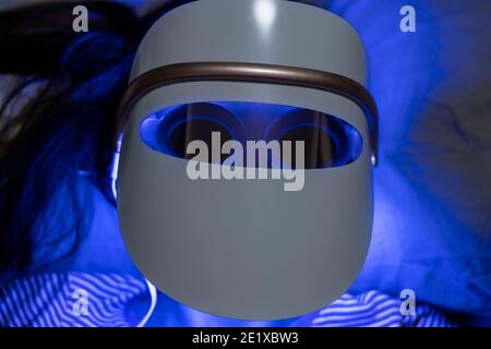 Woman with blue led light therapy facial and neck beauty mask photon therapy Stock Photo