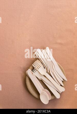 Three piles of wooden cutlery on a dish at the bottom part of the image on a brown background. Stock Photo