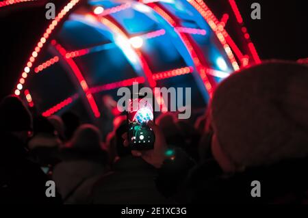 Blurry bokeh Light on a dark background. Defocused Image of an Illuminated outdoor stage area at Night. Unfocused stage lights and crowds with smartph Stock Photo