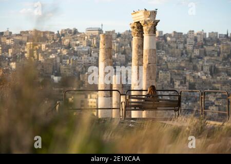 (Selective focus) Stunning view of a girl seated on a bench admiring the landscape from the Citadel of Amman, Jordan. Stock Photo