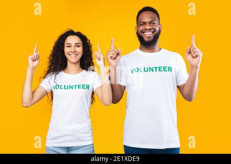Two Volunteers Couple Pointing Fingers Up Posing Over Yellow Background Stock Photo