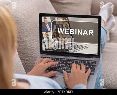 Unrecognizable caucasian lady sitting on sofa and listening to webinar Stock Photo