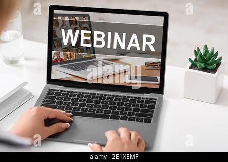 Female hands on laptop keyboard with webinar text on screen Stock Photo