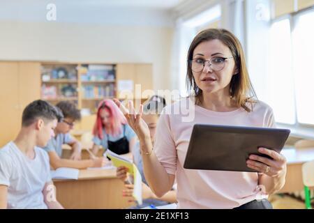 Portrait of mature woman teacher in classroom with digital tablet Stock Photo