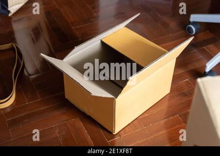 Empty cardboard box on wooden floor. Preparing to relocation. Stock Photo