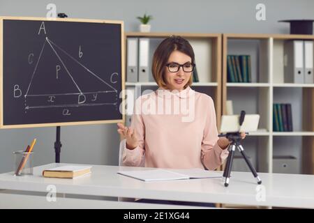 Female math and geometry teacher explains new material to students through a video call. Stock Photo