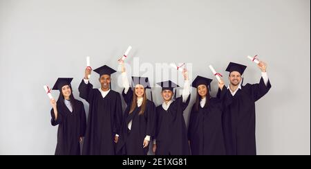 Group of happy multiethnic college or university graduates holding up their diplomas Stock Photo
