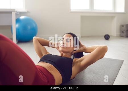 Fit woman doing crunches or sit-ups on gym mat during routine sports workout at home Stock Photo