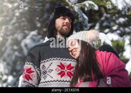 Sweet couple hugging standing in snowy forest Stock Photo