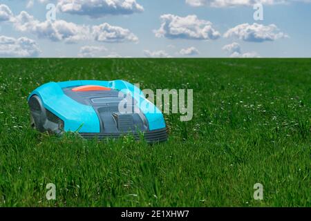 Autonomous lawnmower on the green lawn Stock Photo