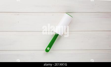 Sticky roller for collecting dust, wool, hair on white wooden background Stock Photo