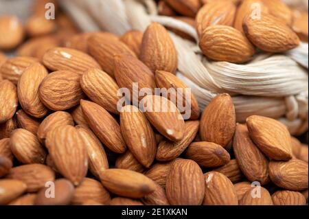 Almonds in a wicker basket and scattered on the table. Close-up, selective focus Stock Photo