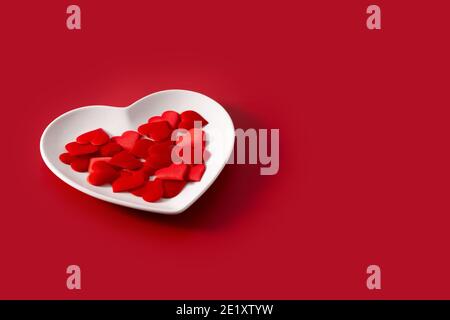 Heart shaped plate with red hearts inside on blue background Stock Photo