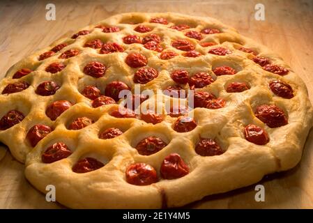 Apulian focaccia, typical bari pizza made with a dough of potatoes and durum wheat flour with cherry tomatoes on top, close up Stock Photo