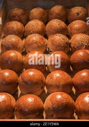 dinner roll pan - many small loaves with and without sesame seeds in wooden tray Stock Photo