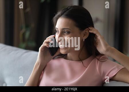 Smiling ethnic woman talk on cellphone at home Stock Photo