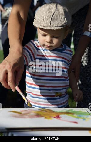 Parent helping his son to paint in park Stock Photo